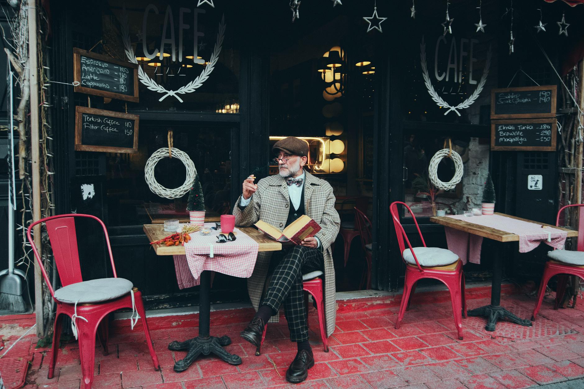 Elegancki mężczyzna z kawą i książką w kawiarni na ulicy w Stambule
