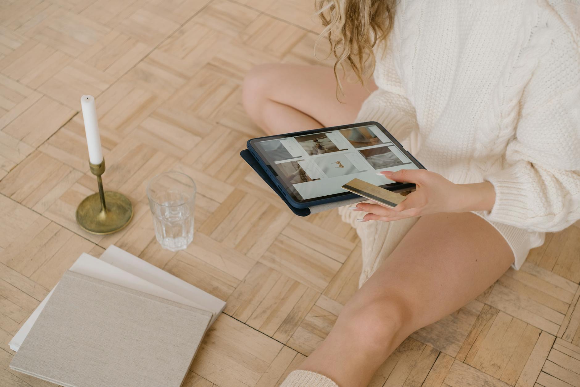 Kobieta robi zakupy online na tablecie, trzymając w dłoni kartę płatniczą