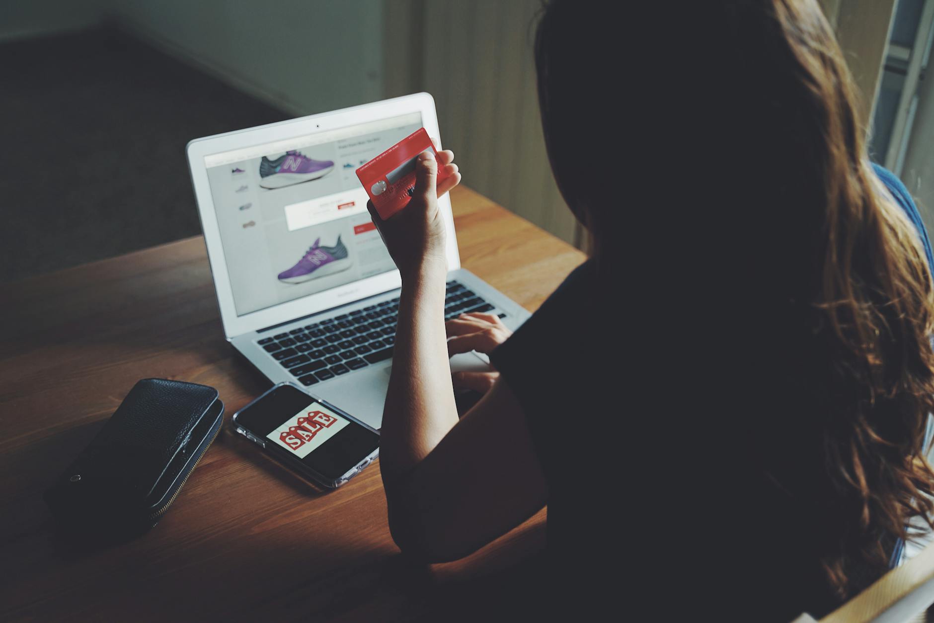 Kobieta robi zakupy online przy laptopie, płacąc kartą na stole