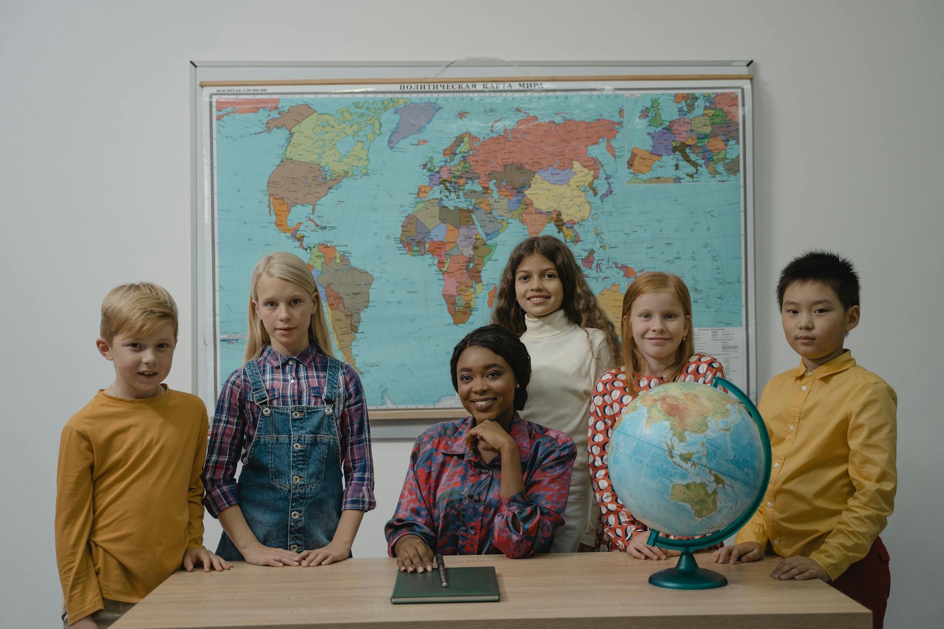 Jak międzynarodowe programy edukacyjne zmieniają polską szkołę: szanse, wyzwania i praktyczne przykłady Nauczyciel i różnorodna grupa uczniów przy globusie i mapie świata