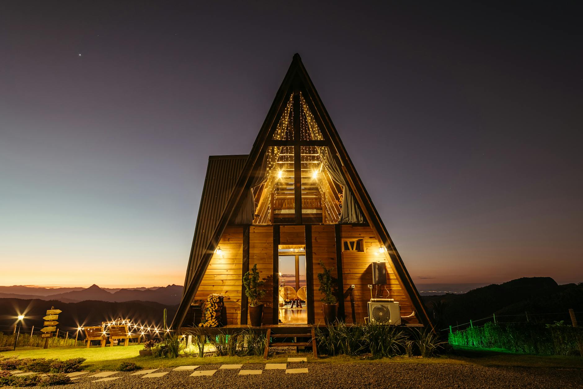 Oświetlona nocą górska chatka A-frame jako klimatyczny nocleg