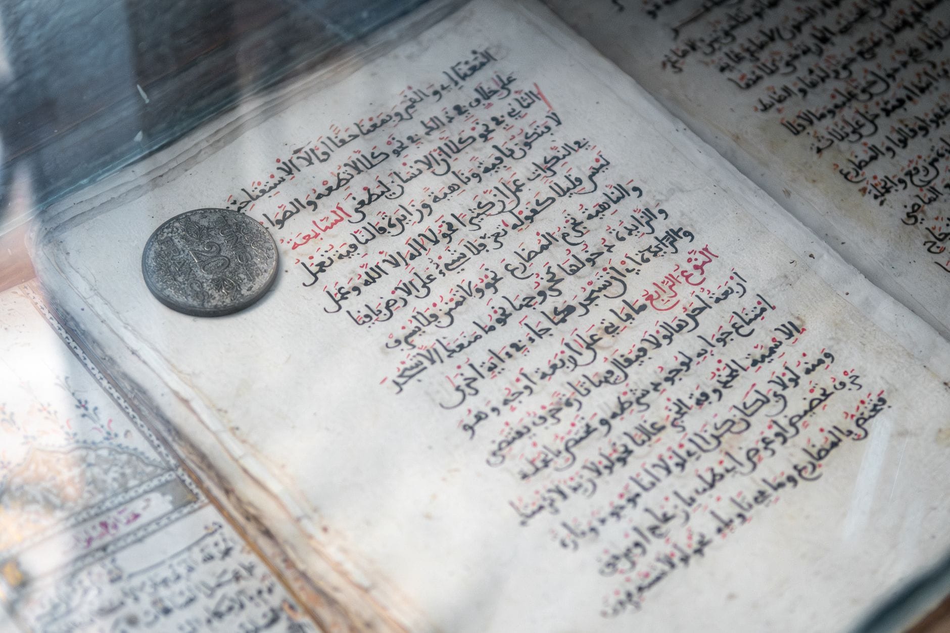 Stare arabskie rękopismo z misterną kaligrafią i zabytową monetą