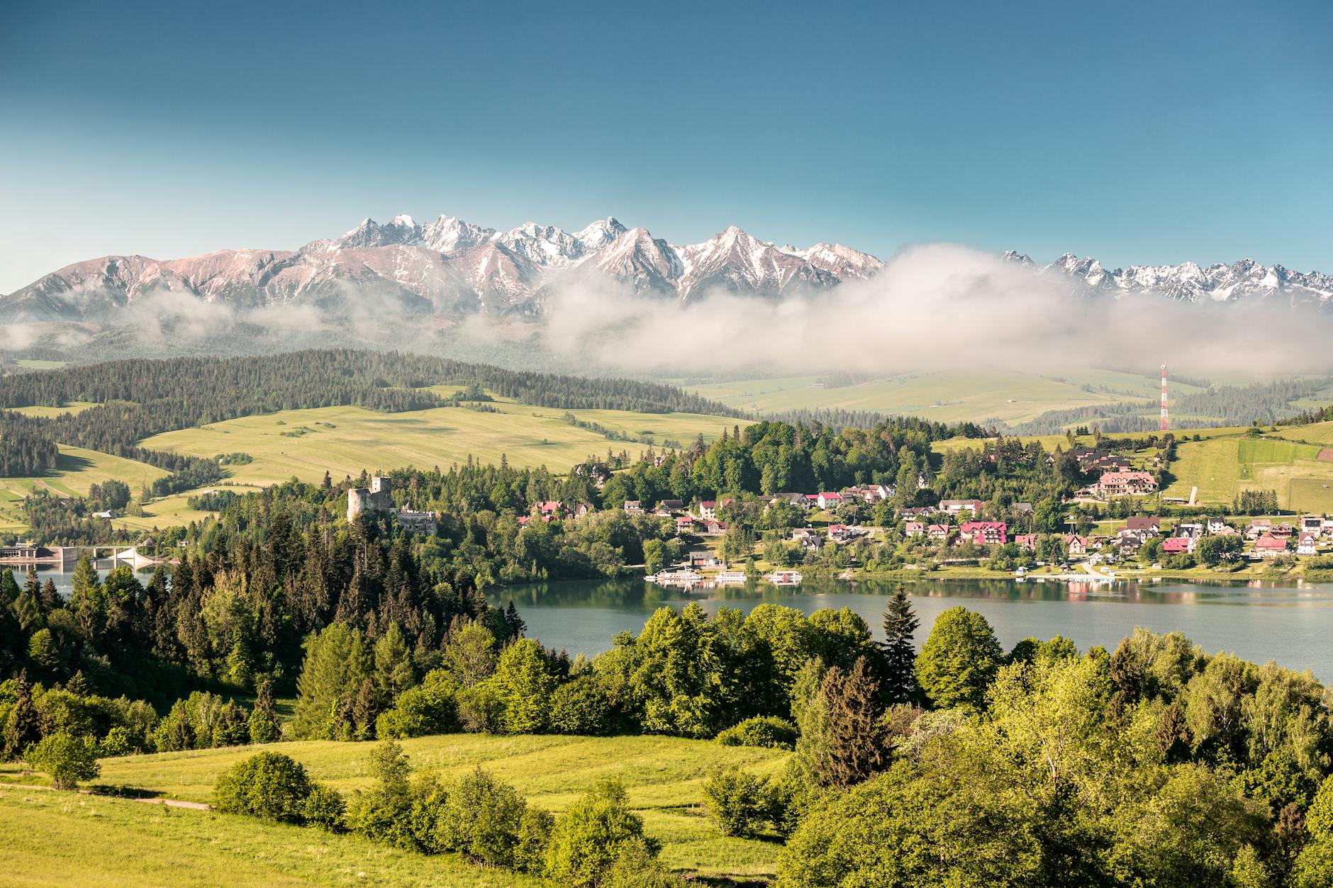 Tatry odbijające się w spokojnym jeziorze otoczonym zielenią