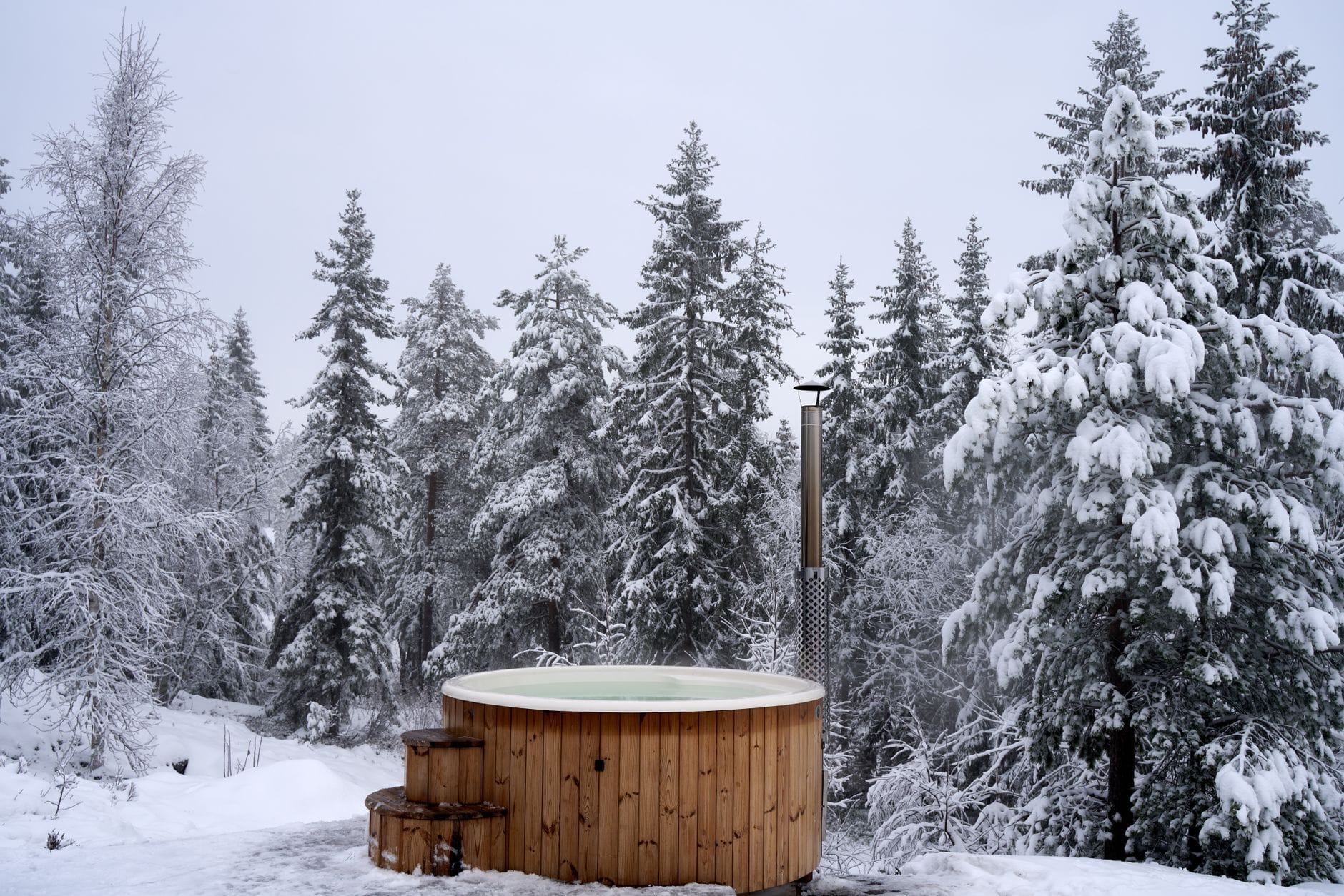 Leśne spa i gorące balie: pomysły na relaksujący wyjazd blisko natury Drewniane jacuzzi w zaśnieżonym lesie sosnowym podczas zimowego wyjazdu